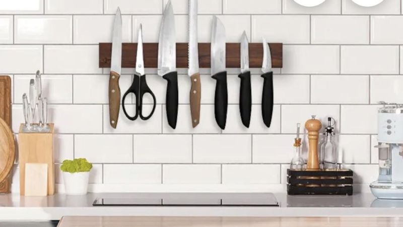 Magnetic knife strip and pegboard holding utensils in a modern kitchen.